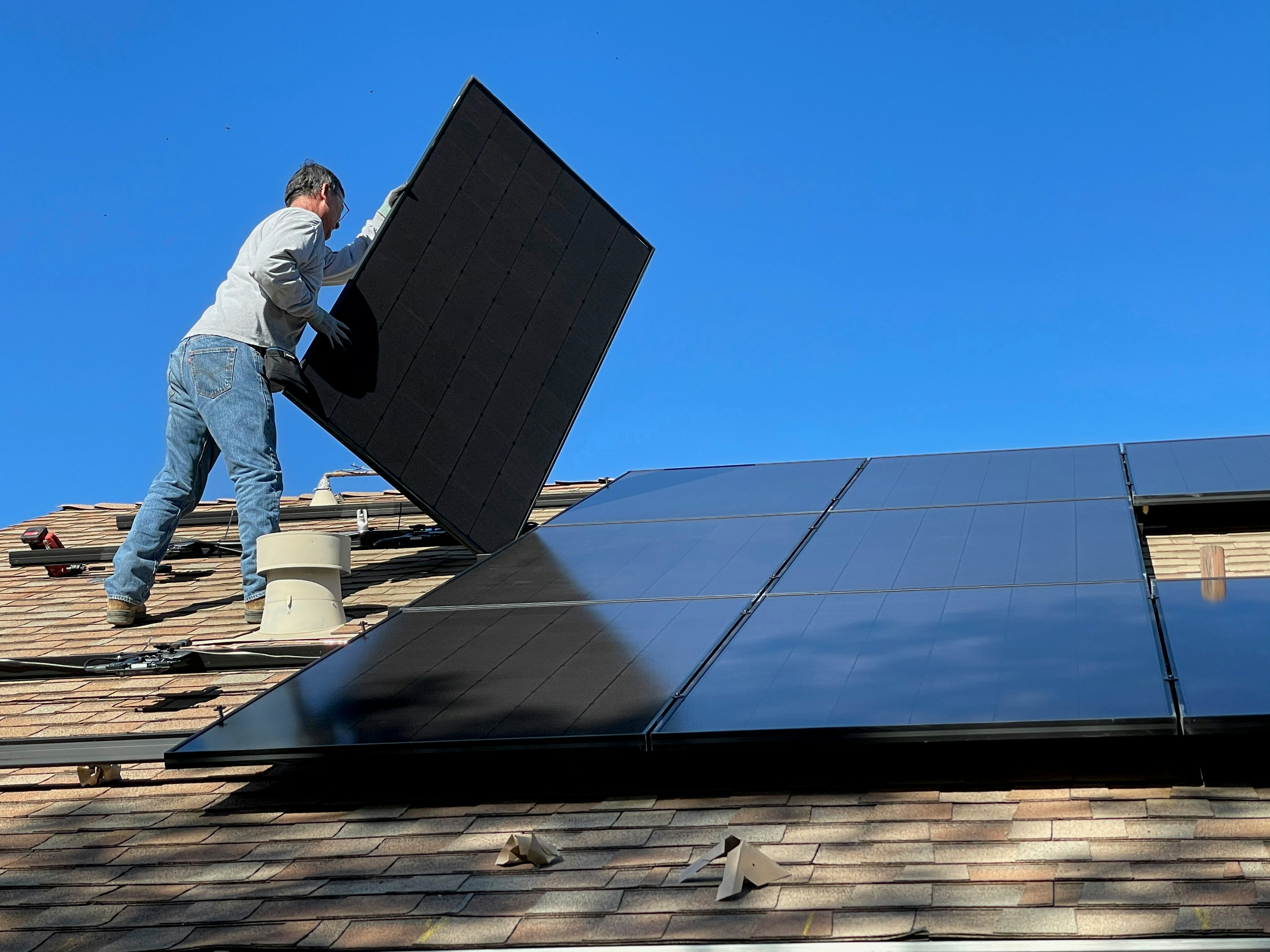 Comparaison visuelle entre panneau solaire monocristallin noir et polycristallin bleuté installés sur toiture